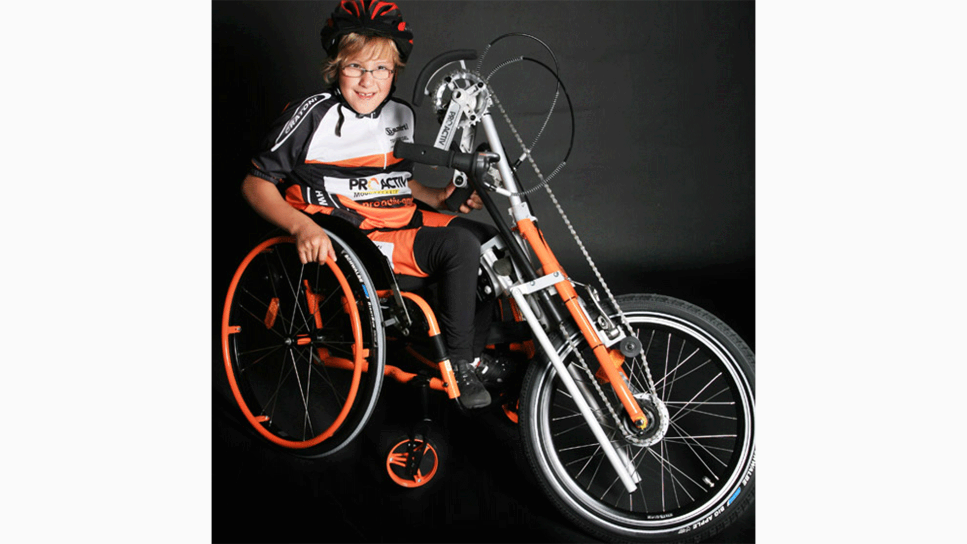 Young boy sits in a wheelchair with a Spike Adaptive bike