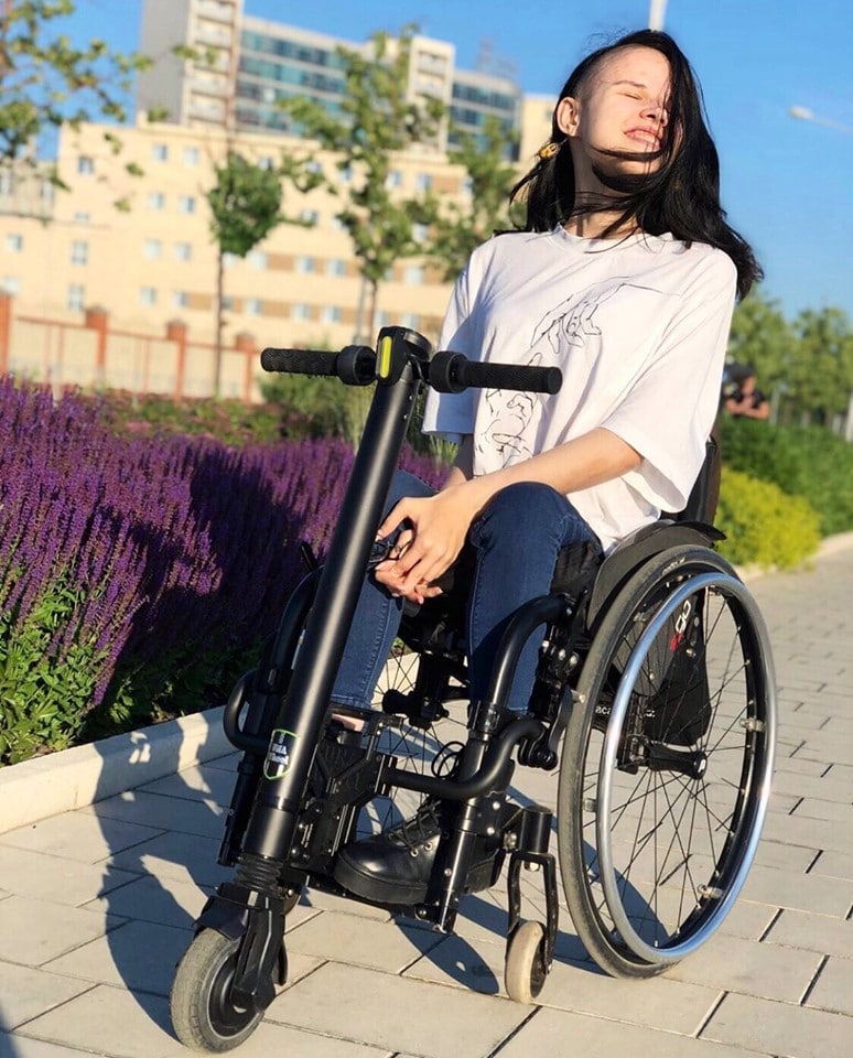 Wheelchair user using the UNAwheel outside in sunny weather